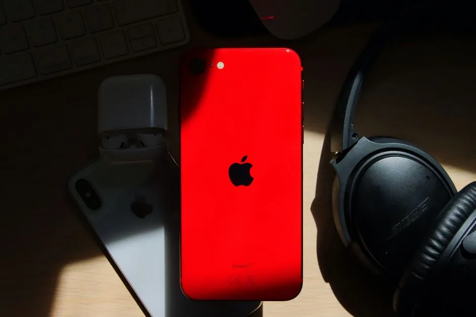 red iphone with airpods nearby