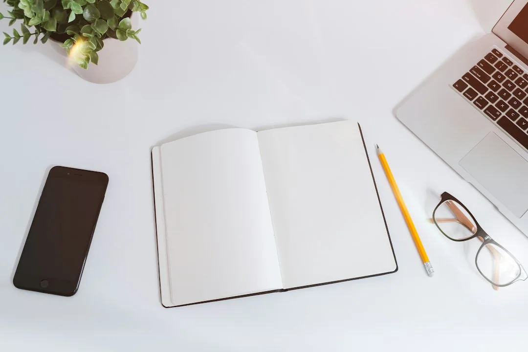 흰 책상 위의 빈 노트와 아이폰, 맥북