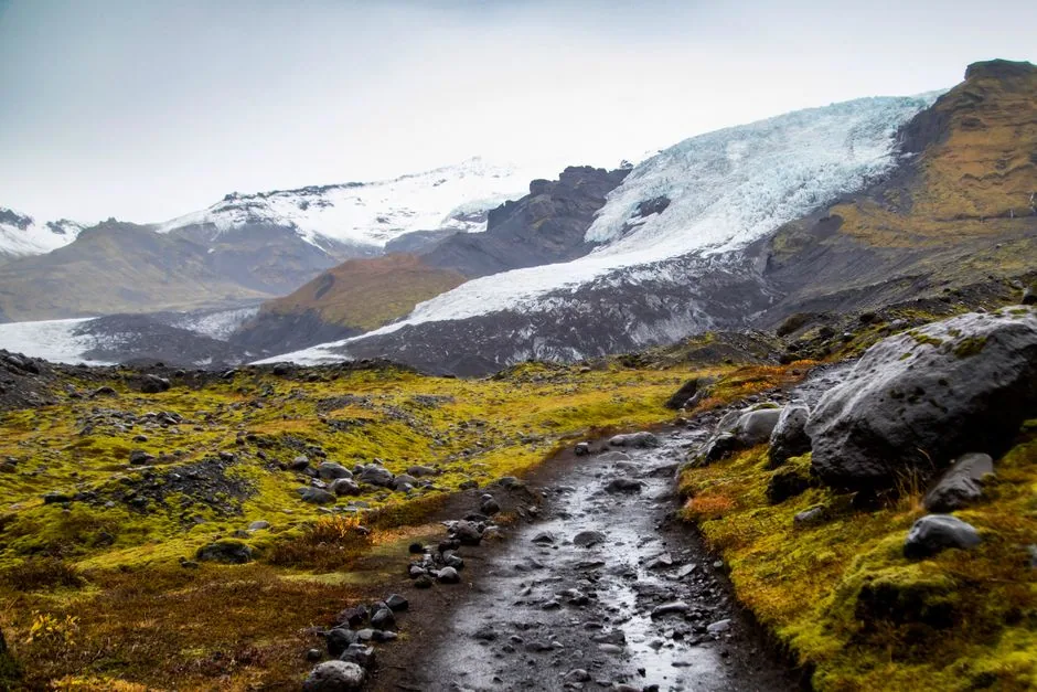 Marked mountain path approaching a glacier landscape