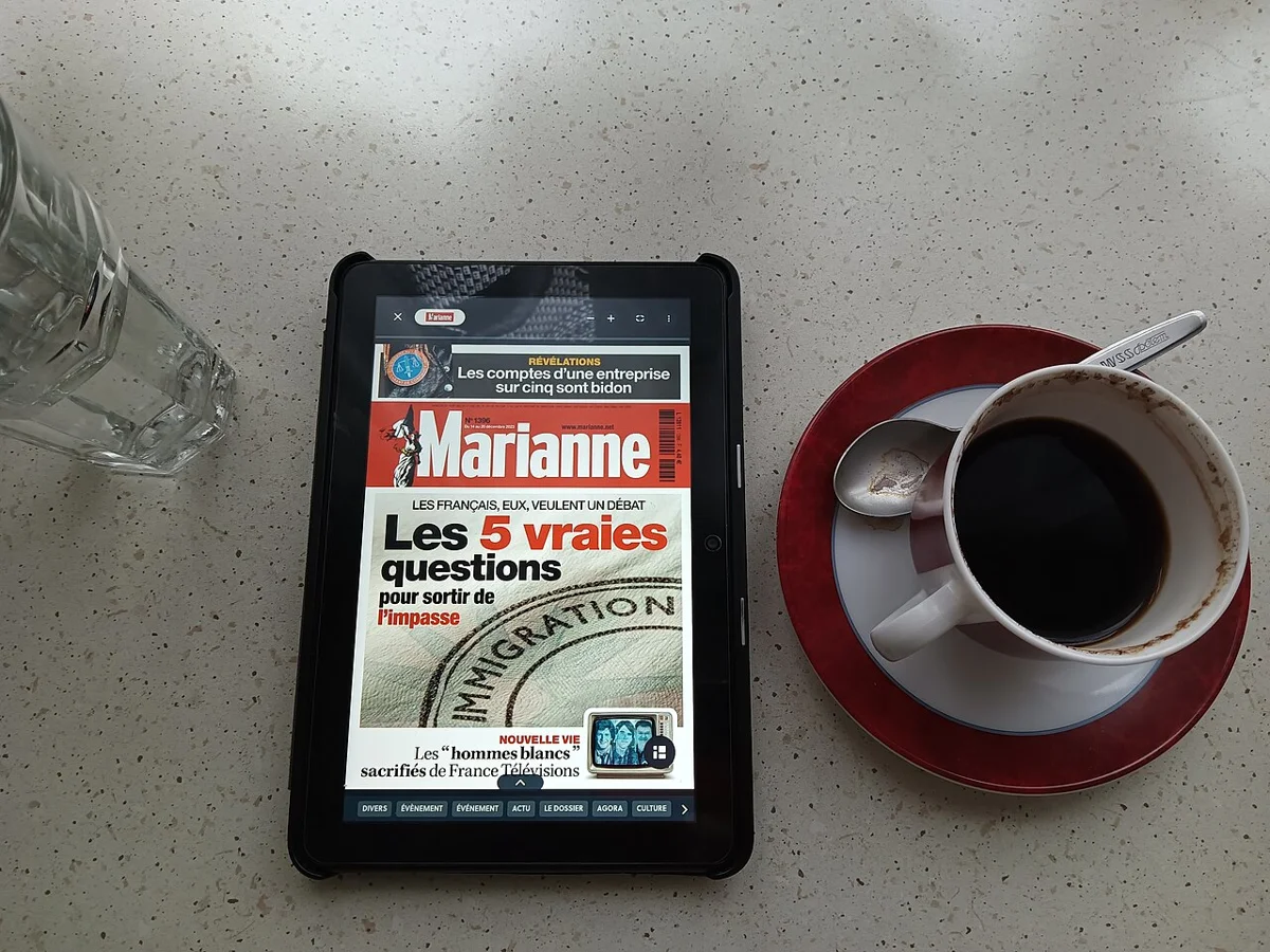 A real photo of an Amazon Fire HD 8 (2022) tablet on a table next to coffee, displaying a news site in a browser. For reference to the previous Fire tablet's appearance only; not the new Alexa Tablet.