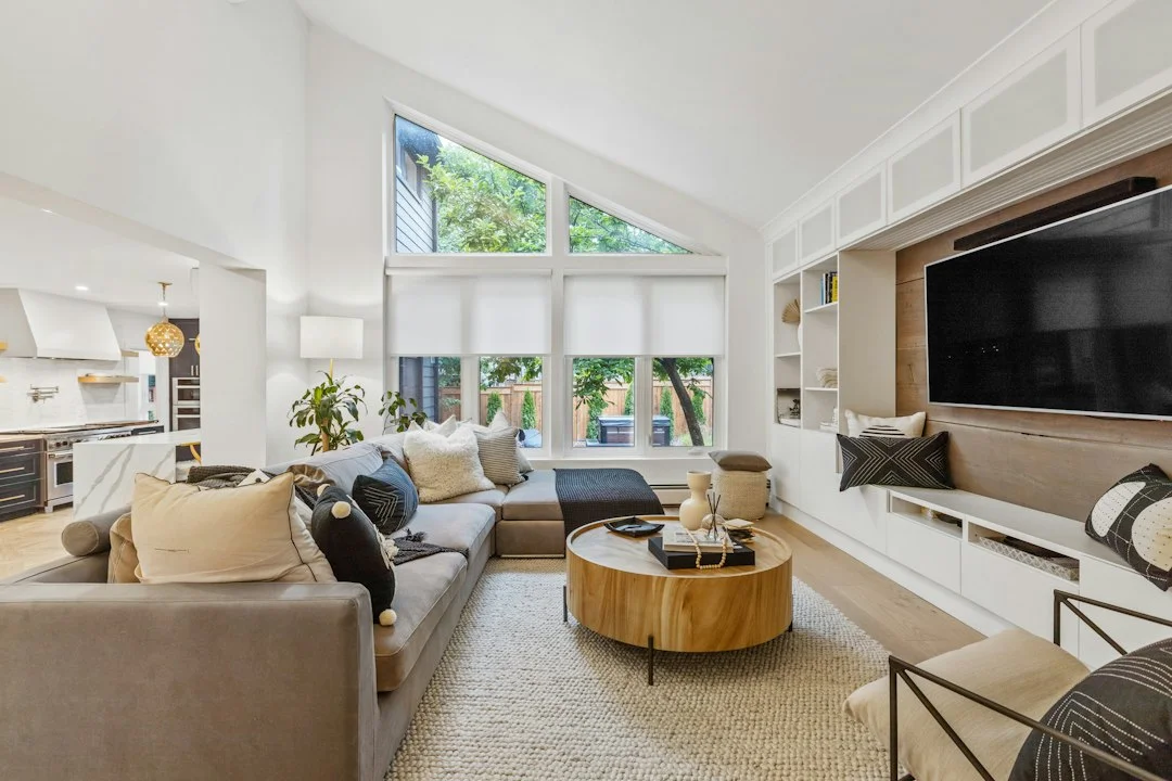 A bright living room interior with a wall-mounted TV and a sofa. This is a neutral reference photo symbolically showing real home viewing conditions, not a voice recognition demo environment.