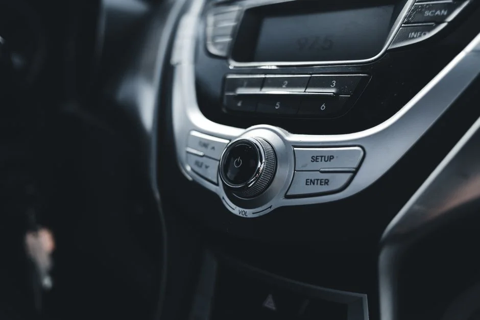 Close-up of audio and climate controls on a car dashboard. A general car radio reference photo showing a volume dial and radio preset buttons; it does not show actual GTA 6 footage or any specific radio station.
